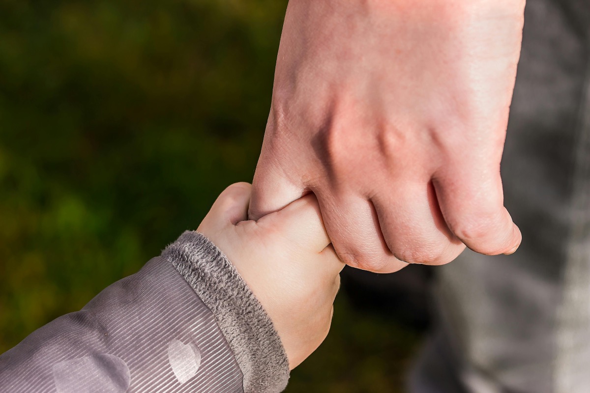 Parent holding child hand representing secure attachment — attachment therapy for families in Charlotte, NC