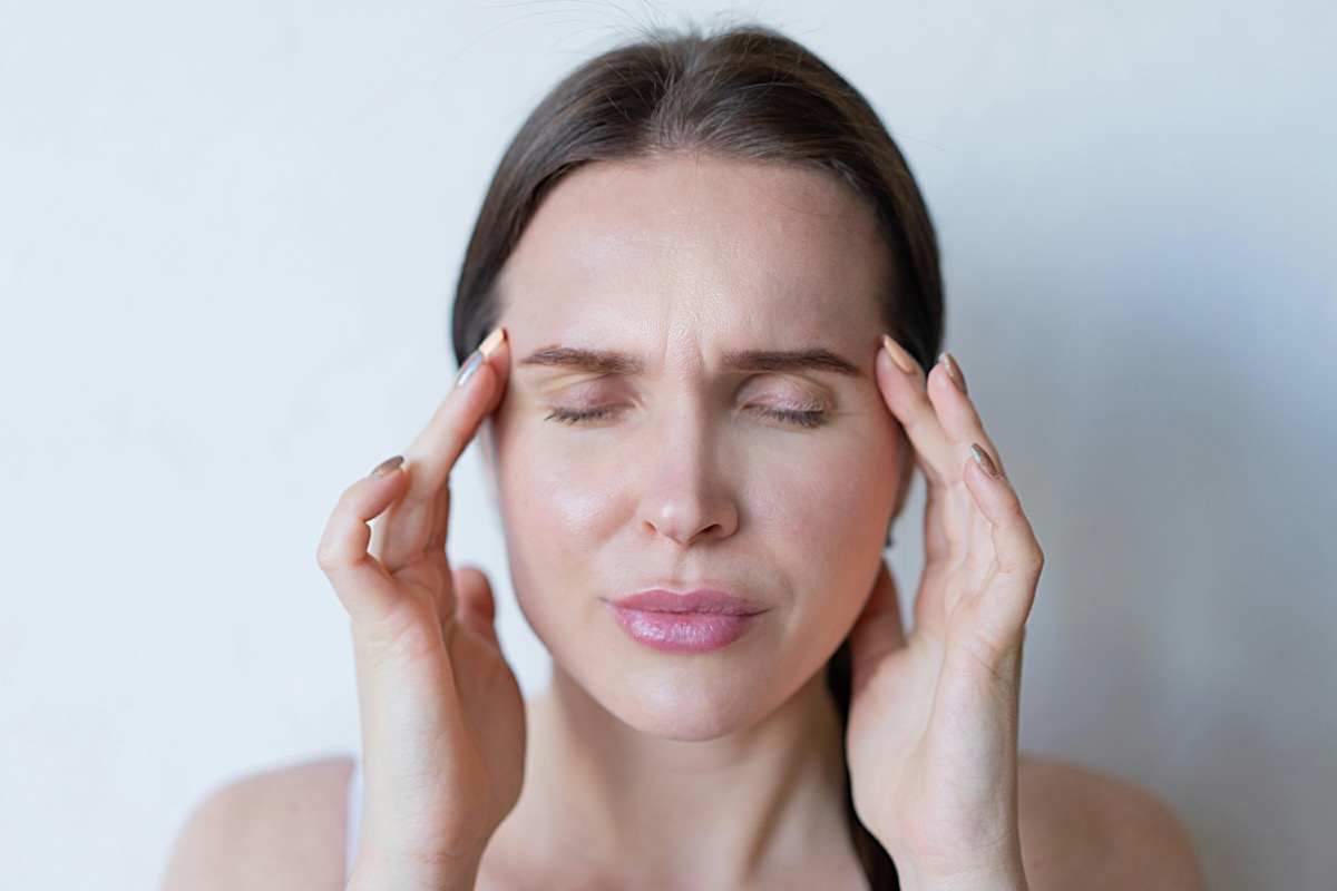 Woman pressing her temples experiencing migraine pain — neurofeedback migraine treatment in Charlotte, NC