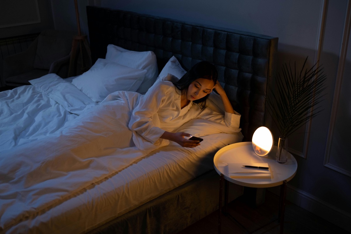 Woman unable to sleep at night checking phone — neurofeedback for insomnia and sleep disorders in Charlotte, NC